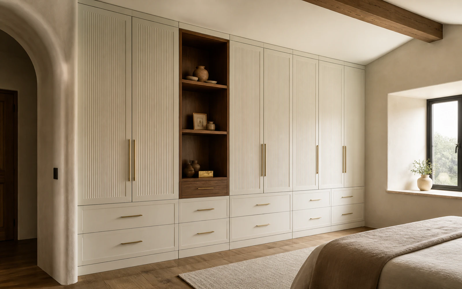 Bedroom wall fitted with tall cream wardrobe cabinets, lower drawers, and a walnut display niche