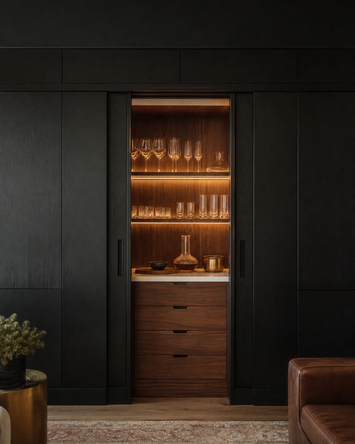 Dark floor-to-ceiling built-in cabinets with an illuminated walnut display niche and drawers